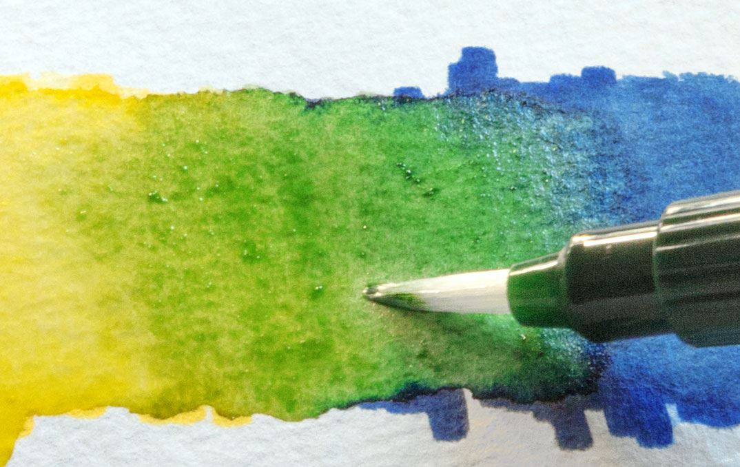 The nib of a watertank brush mixing yellow and blue colours.